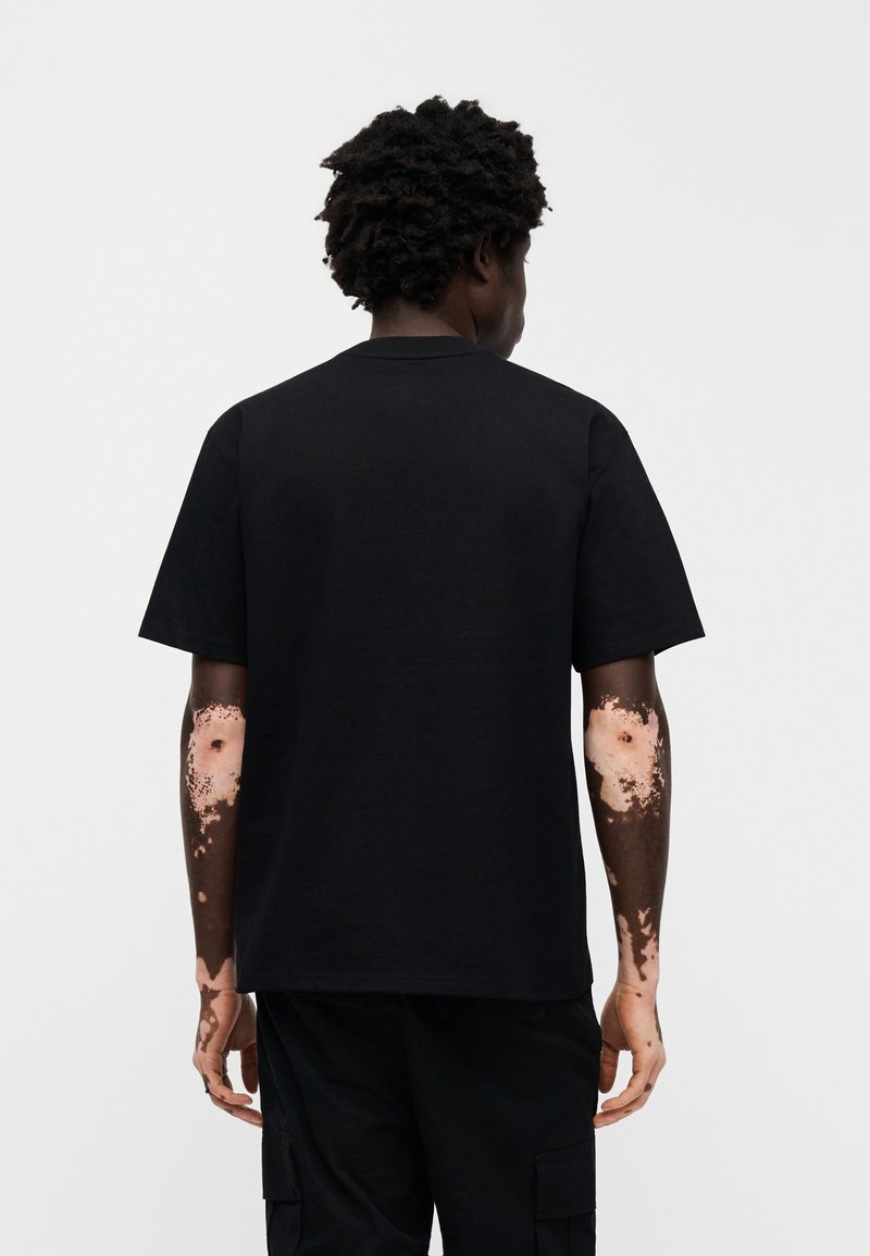 T-shirt di cotone nero con scollo rotondo e maniche corte, caratterizzata da una vestibilità comoda. La vista posteriore non mostra grafiche o motivi.