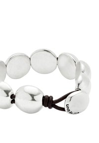 Bracelet en métal argenté avec des maillons lisses et arrondis reliés par un cordon en cuir marron foncé. Marqué "UNO de 50."