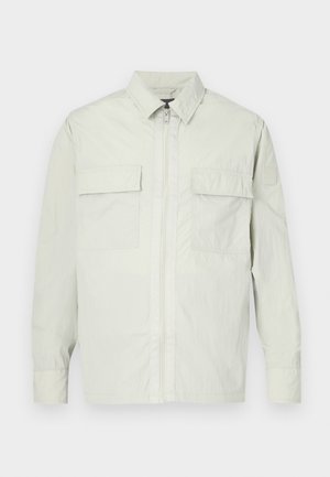 Light gray jacket made of lightweight material, featuring a full zip closure, two front pockets, and a minimal design with a subtle brand logo on the sleeve.