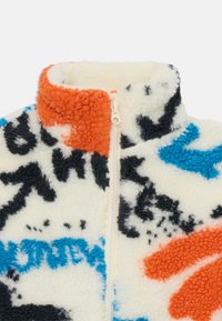 Fleece half-zip jakke med en myk, teksturert overflate. Har flerfargede abstrakte mønstre i oransje, blått, svart og krem.
