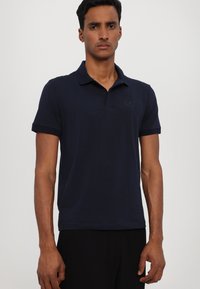 Navy blue polo shirt featuring a collared neck, short sleeves, and a subtle embroidered logo on the chest, made of soft fabric.