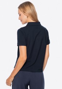 Navy modré polo triko s límečkem a krátkým rukávem, s hladkým povrchem a mírným elastickým efektem. Jednoduchý design, bez vzorů nebo akcentů.