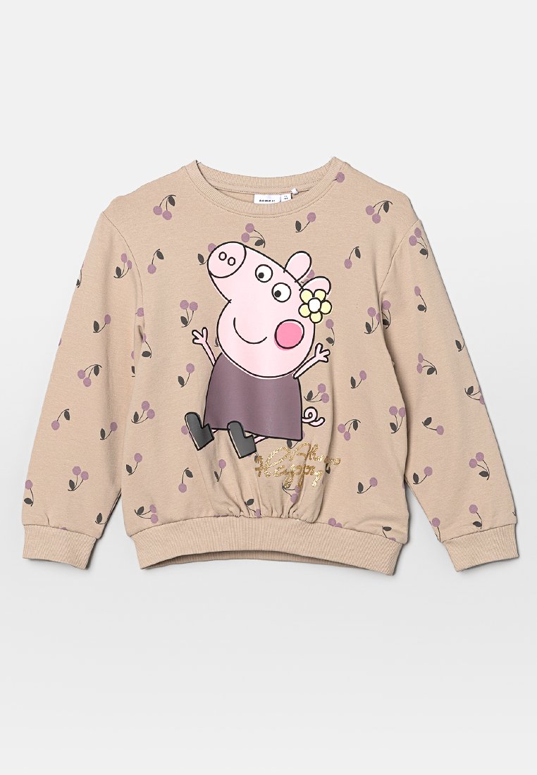 Sudadera beige con un personaje de dibujos animados impreso, que lleva una flor y una falda, adornada con patrones florales en púrpura y negro y un dobladillo elástico.