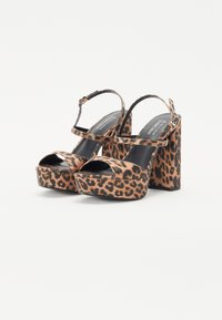 Sandales à talons hauts imprimées léopard avec une plateforme, dotées d'une sangle noire sur les orteils et à la cheville, et d'un épais talon bloc.