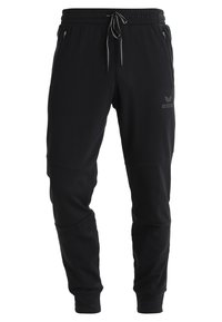 Pantalons de sport noirs au design fuselé, taille élastique, cordon de serrage, poches latérales et un logo discret sur la cuisse.