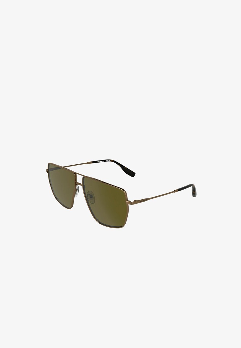 Lunettes de soleil carrées de style aviateur avec une fine monture en métal bronze et des verres verts foncés, inclinées sur fond blanc.