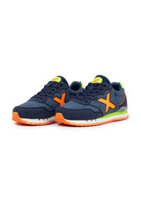 Zapatillas navy con acentos naranjas y parte superior de ante texturizado. Presentan un cuello acolchado y una media suela blanca con una suela naranja.