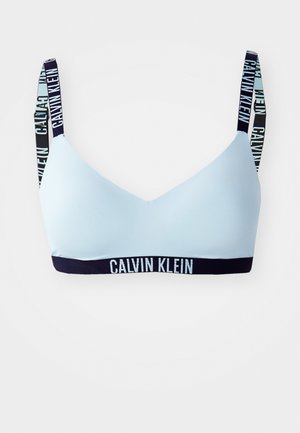 Light blue bralette made of smooth fabric with black and white branded straps. Features a stretchy band with "CALVIN KLEIN" logo.