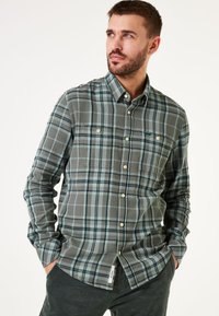 Groene en blauwe geruite button-up shirt met twee borstzakken en een gebogen zoom. Gemaakt van zachte stof met een gestructureerd oppervlak.