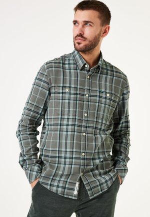 Grün und blau karierter Button-Up-Hemd mit zwei Brusttaschen und abgerundetem Saum. Hergestellt aus weichem Stoff mit strukturierten Oberfläche.