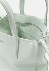 Borsa a mano in pelle verde menta con texture liscia, tasca con zip e scomparti interni; presenta manici corti e logo in rilievo.