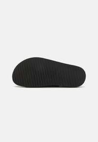 Black shoe sole with a ribbed texture, featuring a rounded toe and an extended heel area. Flat design suitable for casual footwear.