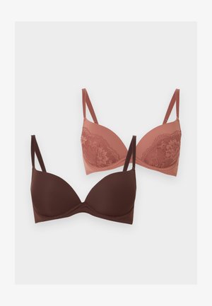 Δύο σουτιέν, ένα μονόχρωμο σκούρο καφέ και ένα σε χρώμα σκόνης ροζ με δαντελένιες λεπτομέρειες, και τα δύο με ρυθμιζόμενους ιμάντες σε λευκό φόντο.
