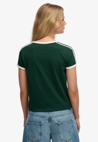 Groen katoenen T-shirt met korte mouwen en een ronde hals, met crèmekleurige accenten op de kraag en mouwranden.