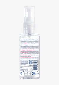 Bouteille pulvérisatrice en plastique transparent avec une pompe blanche amovible, étiquetée en plusieurs langues, contenant un spray apaisant pour la peau destiné à soulager les rougeurs.