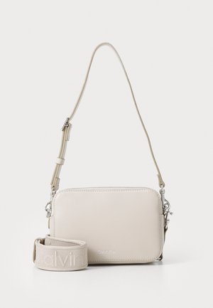Light beige crossbody bag with smooth leather texture, silver hardware, and a detachable strap featuring embossed logo. Rectangular shape.