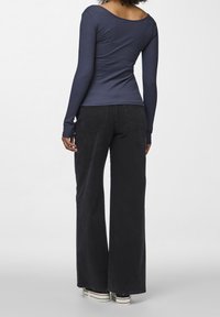 Långärmad marinblå ribbad topp i kombination med svarta vida byxor. Outfiten har en rundad halsringning och textil med struktur för extra detalj.