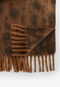 Écharpe en laine marron avec un motif à pois, des bords frangés et une texture douce, présentant des nuances chaudes de marron et des accents noirs.