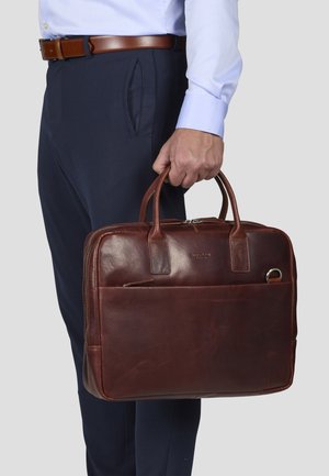 Brown leather briefcase with dual handles, zipper closure, and front pocket. Smooth texture with minimal branding and a sleek design.