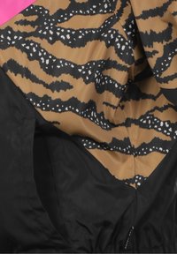 Hnědá a černá látka se vzorem tygřího pruhu, doplněná růžovými a černými sekcemi. Hladký a lesklý povrch.