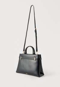 Črna usnjena torbica s kratkimi ročaji in dolgim nastavljivim naramnim trakom, obešena na belem ozadju.