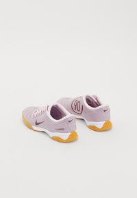 Nike total90 III shoes, featuring a soft pink upper, orange outsole, white midsoles, and embroidered "90" detail. Smooth texture throughout.