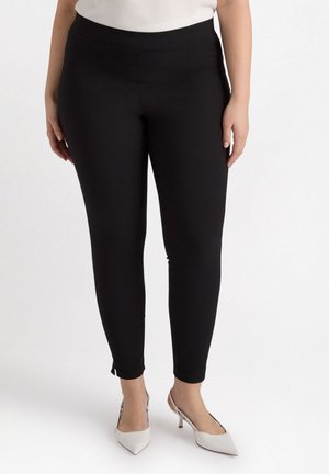Zwarte leggings met een slim fit, gemaakt van rekbare stof. Voorzien van een elastische tailleband en kleine openingen bij de enkels voor detail.