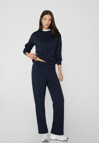 Marineblauwe sweatshirt met lange mouwen en een afgeronde onderrand, gecombineerd met bijpassende broek. Beide items hebben een gladde, zachte textuur.