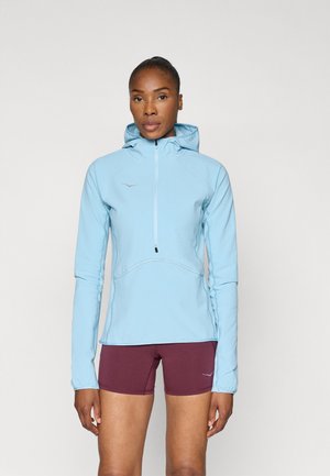 Sweatshirt azul claro com fecho éclair, acabamento texturizado, capuz ajustável e detalhes refletivos, combinado com calções bordô.