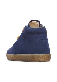 Scarpa alla caviglia in suede blu navy con tomaia testurizzata, suola tonda color tan e lacci arancioni a contrasto. Presenta un design cucito e un logo.