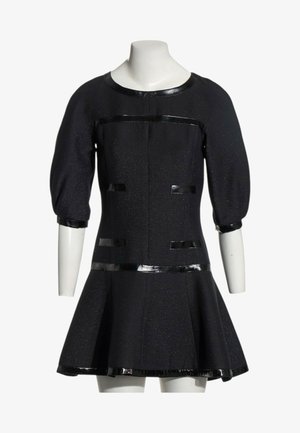 Robe noire avec manches bouffantes jusqu'au coude, bordure brillante sur l'encolure, les poignets, la taille, les poches et l'ourlet, exposée sur un buste de mannequin blanc.