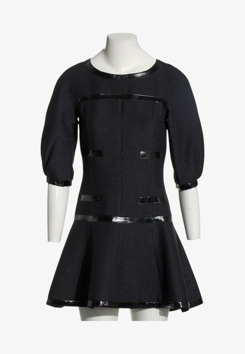 Robe noire avec manches bouffantes jusqu'au coude, bordure brillante sur l'encolure, les poignets, la taille, les poches et l'ourlet, exposée sur un buste de mannequin blanc.