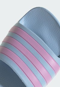 Blue slide sandal featuring three pink horizontal stripes, textured upper, and smooth sole. The design is lightweight and casual.