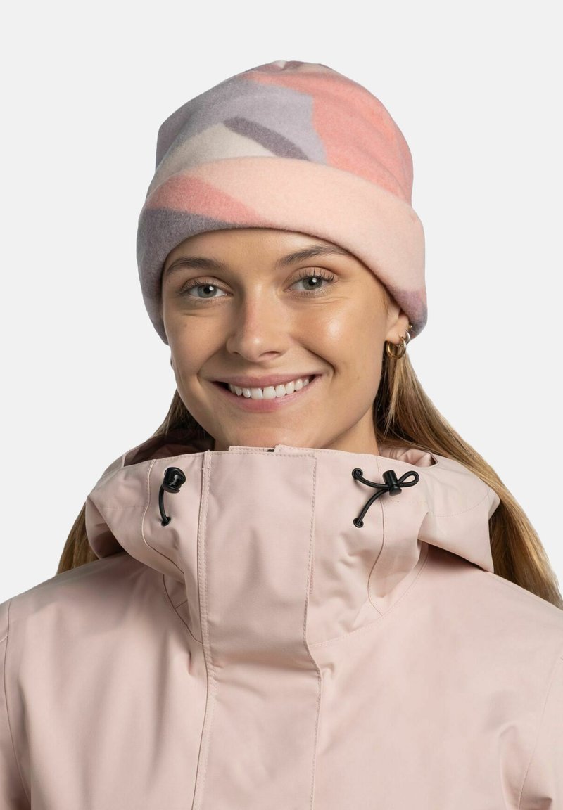 Gorro de forro polar en colores pastel (rosa, púrpura, gris) con puño enrollado. El modelo lleva una chaqueta rosa claro con cierres de cordón.