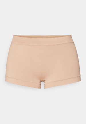 Nude elastic shorts with a soft texture, featuring a wide waistband and a cut-out detail at the hem, designed for comfort and flexibility.