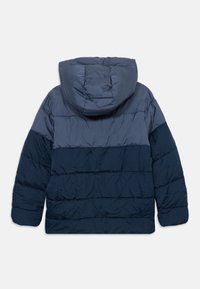 Veste matelassée bleu marine bicolore avec capuche, présentant des coutures matelassées horizontales et des manches longues, vue de dos.