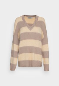 V-ringad oversize tröja med breda horisontella beige och taupe ränder, ribbade ärmslut och nederkant, uppvisad mot en vit bakgrund.