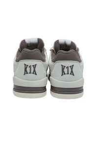Weiße Wildledersneaker mit braunen Akzenten, featuring einen gepolsterten Schaft und dem 'K1X'-Logo an der Ferse. Flache Gummisohle. Zwei Ösen für Schnürsenkel.