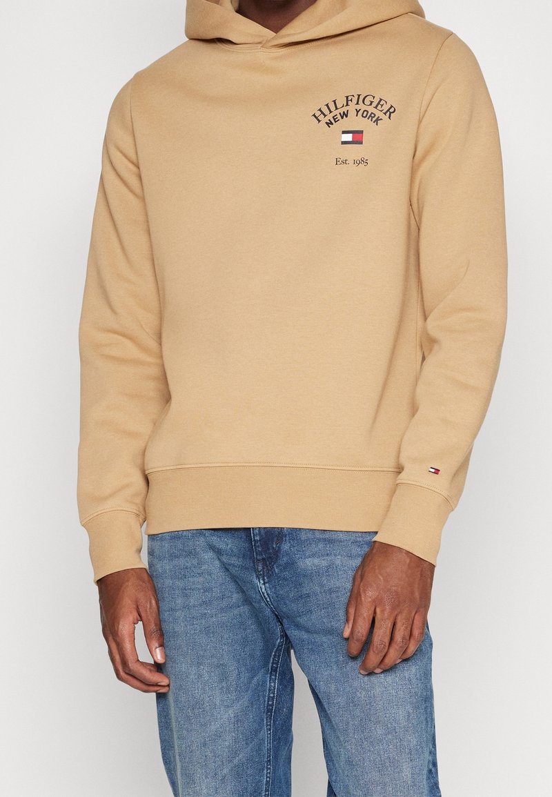 Felpa beige con cappuccio regolabile, tasca a marsupio e logo ricamato "HILFIGER NEW YORK". Tessuto morbido con polsini e orlo a coste.
