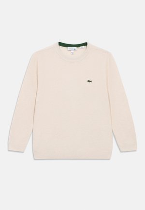 Pulover bej deschis cu guler rotund, mâneci lungi și tricot texturat. Are un mic logo cu crocodil verde pe partea stângă a pieptului.