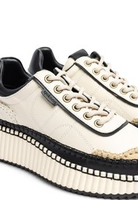 Sneaker platform in crema e nero con tomaia in pelle, punta tonda, occhielli in metallo e cuciture a contrasto. Suola in gomma testurizzata.
