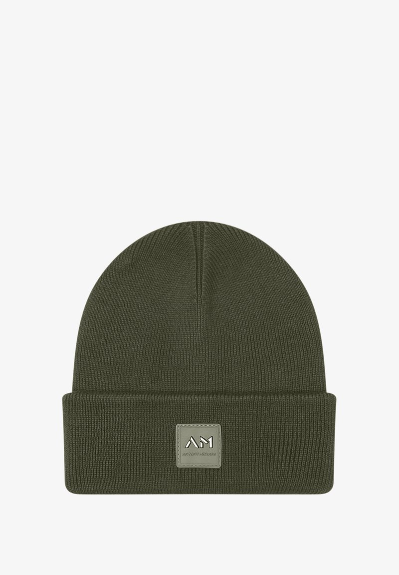 Gorro de punto verde oliva con un borde doblado y una etiqueta cuadrada que presenta un logo en relieve. Textura suave, diseño ajustado.
