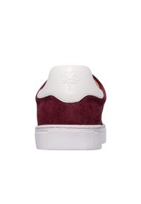 Rdeč semiš superga z belim usnjenim ovratnikom na peti, z večplastnimi teksturami in reliefno logotipom na zadnji strani. Ravna gumijasta podplata z vzorcem za oprijem.