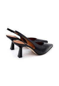 Scarpe slingback in vernice nera con punte affusolate e tacco quadrato. Texture liscia con accenti minimi e dettagli laterali intagliati.