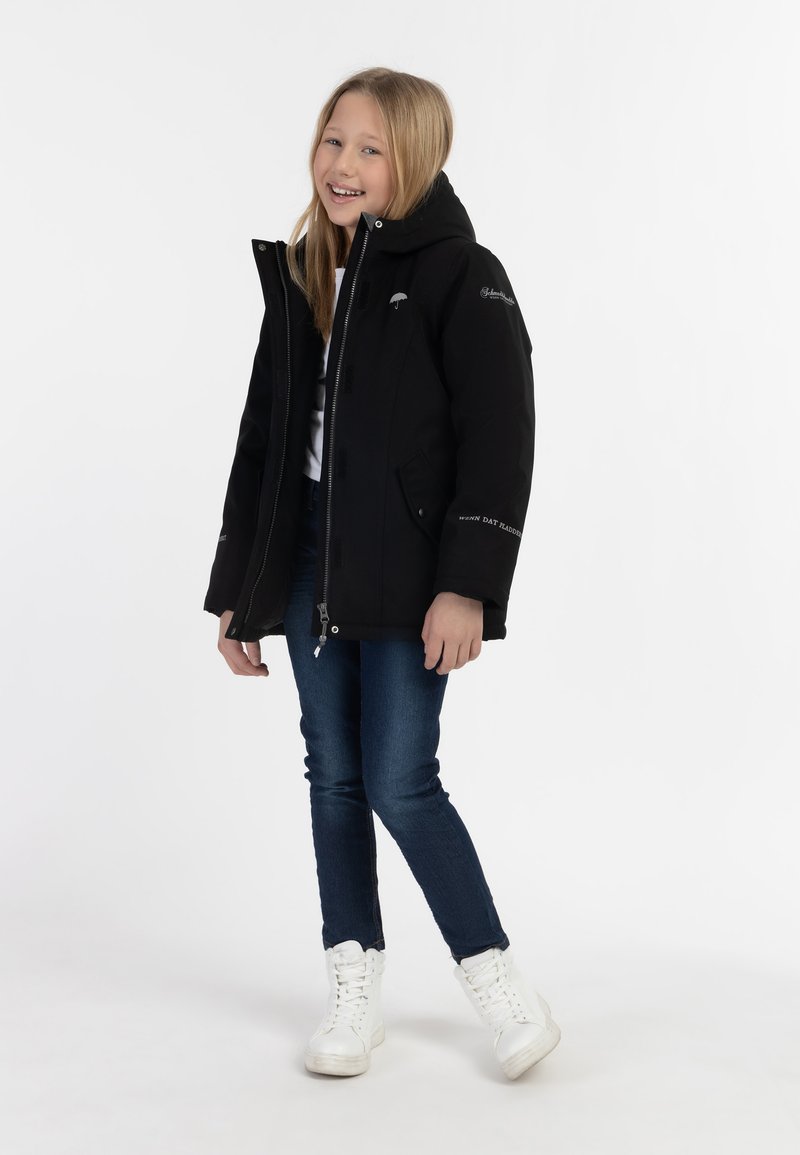 Svart isolerad jacka med huva, dragkedja och sidofickor; bärs över en vit topp och blå jeans; matchas med vita sneakers.