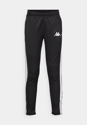 Zwarte sportbroeken met witte zijkanten, een elastische tailleband en een klein wit logo op de linkse heup. Glad textuur, aansluitend ontwerp.
