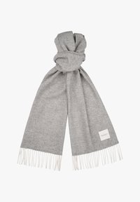 Grå uldscarf med en tekstureret overflade, prydet med hvide frynser i enderne og et lille mærke. Bundet i en løs knude.