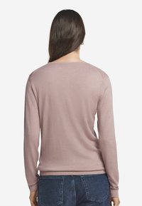 Rosa Langarmpullover mit Rundhalsausschnitt, glatter Textur, gerippten Bündchen und Saum, getragen mit blauen Jeans.