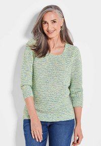 Strickpullover in Hellgrün mit mehrfarbigen Sprenkeln, rundem Ausschnitt und Dreiviertelarmen. Kombiniert mit blauen Jeans.