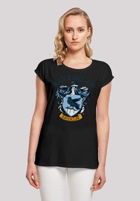 Must t-särk lühikeste varrukatega mustal taustal, millel on sinine ja hõbedane Ravenclawi vapp, mille kohal on tekst "RAVENCLAW" ja all riba. Pehme kangas, mugav lõige.